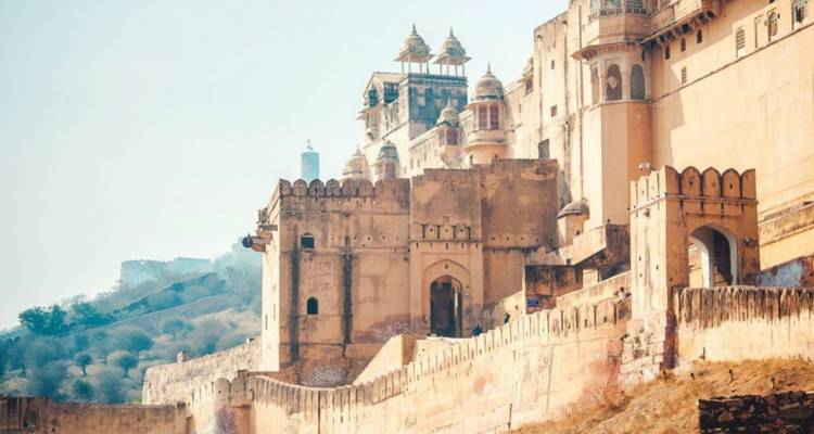 Las murallas de piedra arenisca y las cúpulas ornamentadas del Fuerte Amber brillando bajo la suave luz matutina contra colinas brumosas