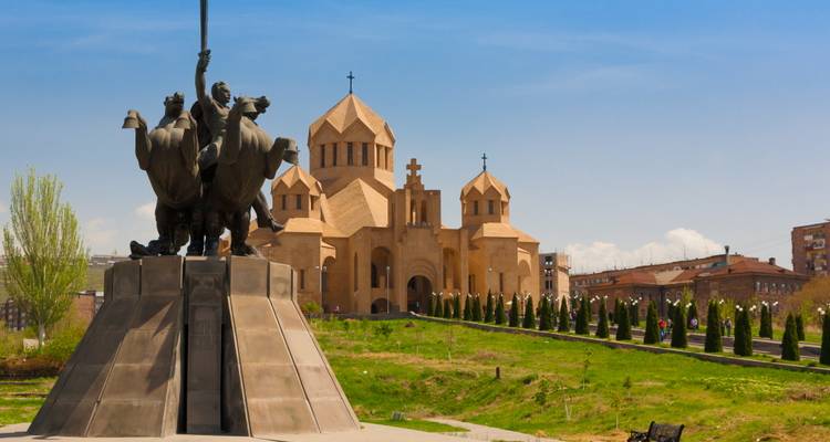 Estatua monumento frente a la moderna Catedral de San Gregorio el Iluminador rodeada de césped cuidado en Ereván.