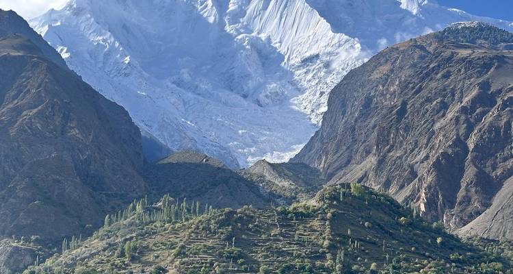 Snow-covered Nanga Parbat massif towering above lush terraced valley in northern Pakistan