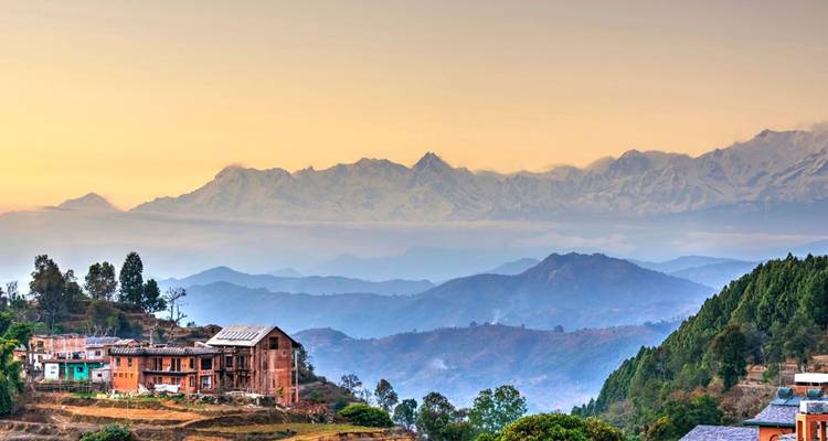 Tranquilo pueblo de montaña al amanecer con crestas azules escalonadas y picos nevados que brillan bajo cielos pastel.