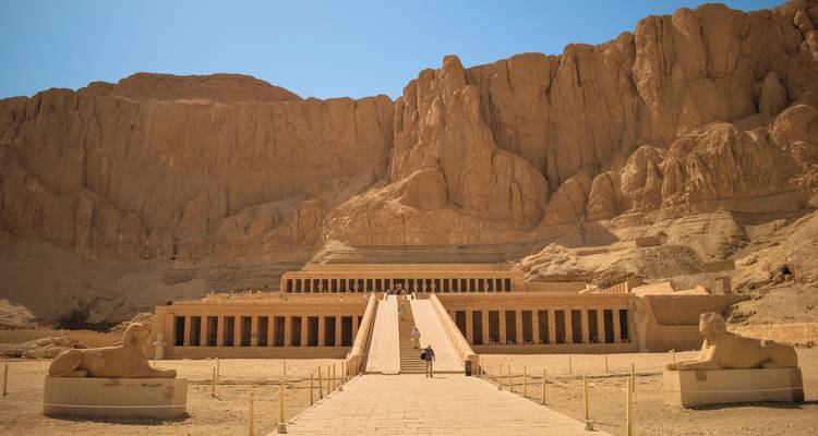 Der Tempel der Hatschepsut schmiegt sich unter einem klaren blauen Himmel an hohe Klippen in Luxor.