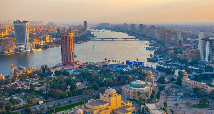 Luftaufnahme von Kairo bei Sonnenuntergang mit dem Nil, der sich durch die beleuchtete Stadt schlängelt.