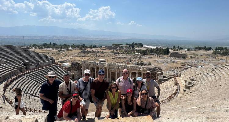 Grupo de turistas posa en las gradas de piedra del antiguo teatro de Hierápolis con vista a las llanuras de Pamukkale.