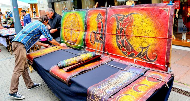 Verkopers rollen kleurrijke leren kunstwerken uit bij een openluchtmarktkraam.