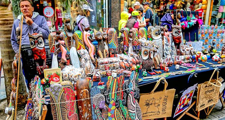 Straatkraam die overloopt van levendige gesneden uilensouvenirs en handwerkartikelen.