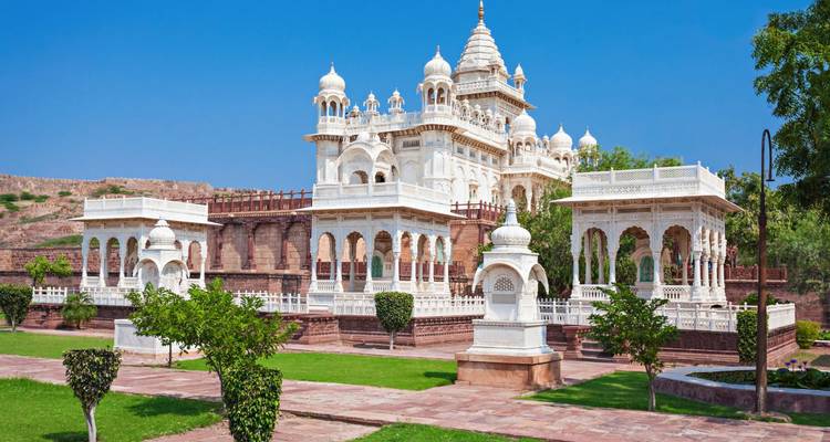Wit marmeren cenotaaf complex gelegen te midden van groene gazons onder een levendige blauwe hemel.