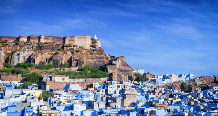 Het iconische fort Mehrangarh torent boven de uitgestrekte blauwe huizen van Jodhpur uit onder heldere luchten.