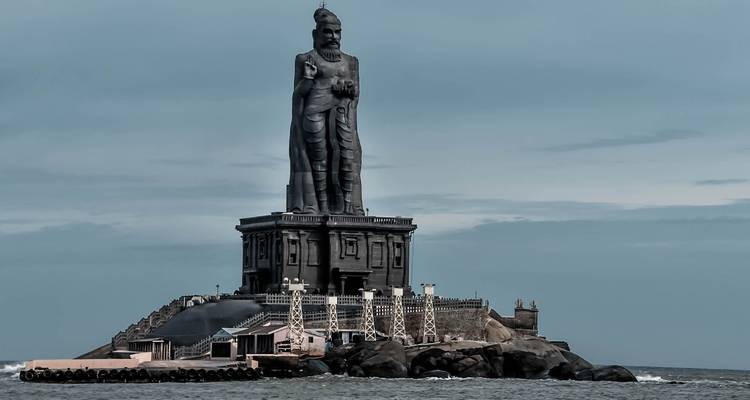 Statue massive de Thiruvalluvar sur un îlot rocheux à Kanyakumari sous un ciel dramatique.
