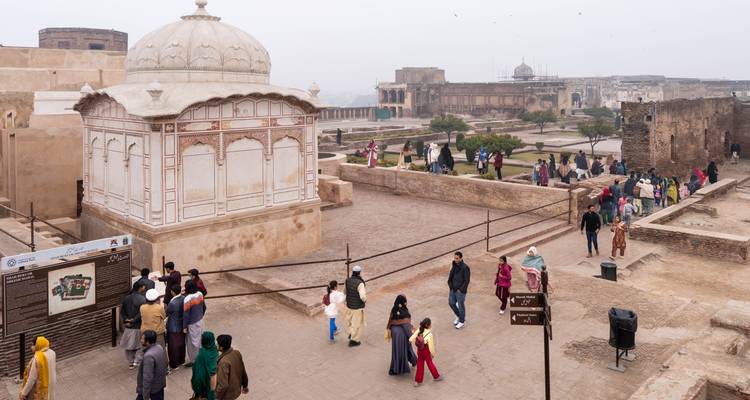 Visiteurs explorant de vastes ruines de fort avec un pavillon à dôme et un arrière-plan brumeux.