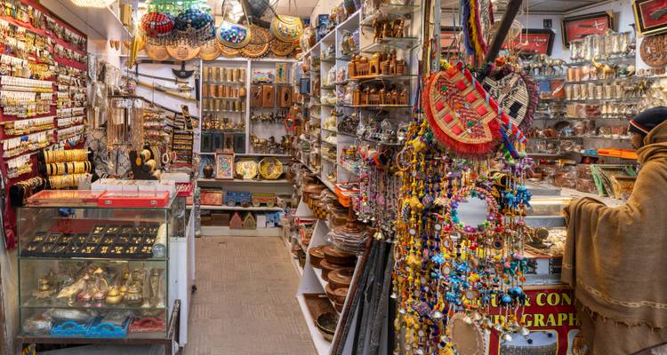 Boutique d'artisanat et de souvenirs colorée remplie d'articles traditionnels pakistanais avec un client qui fait du shopping.