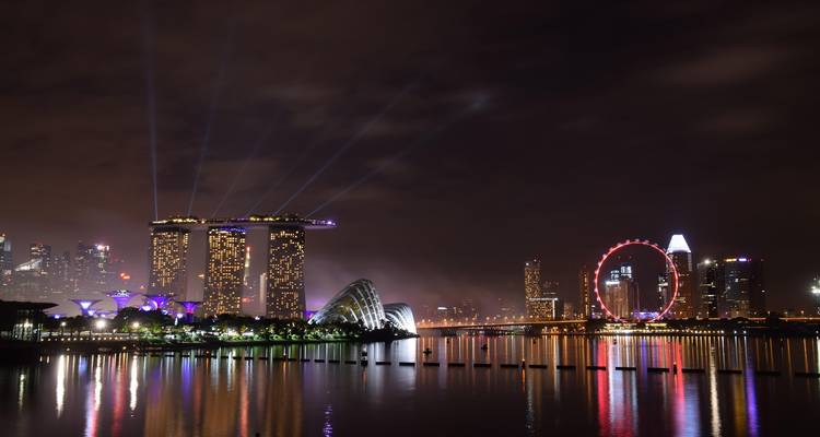 Panorama nocturne du Marina Bay Sands, de la Singapore Flyer et de l'horizon se reflétant dans l'eau.