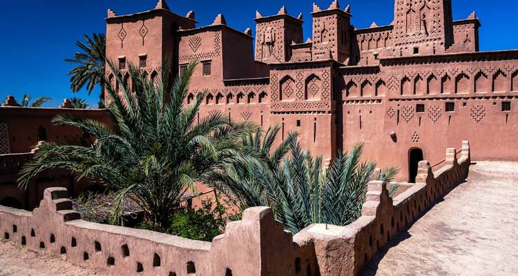 Complejo de kasba de tierra con palmeras y cielo cobalto en la región de Ouarzazate.
