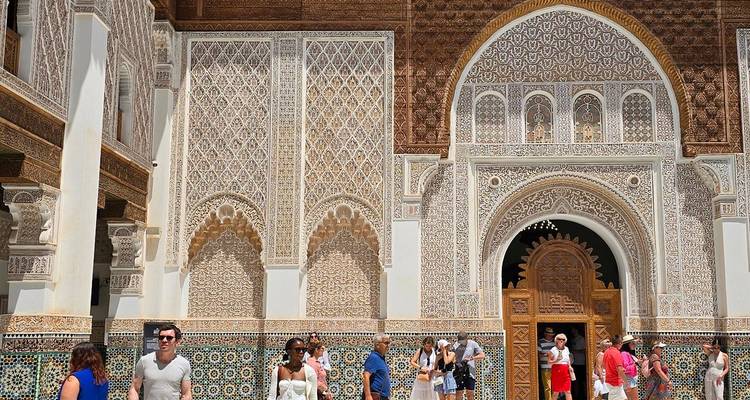 Toeristen verzamelden zich rond de sierlijke gevel van een Marokkaanse madrasa die rijkelijk versierd was met mozaïeken.