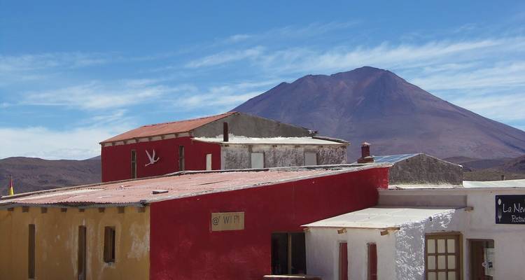 Structures en adobe colorées sous un pic volcanique dans les hautes terres désertiques de Bolivie.