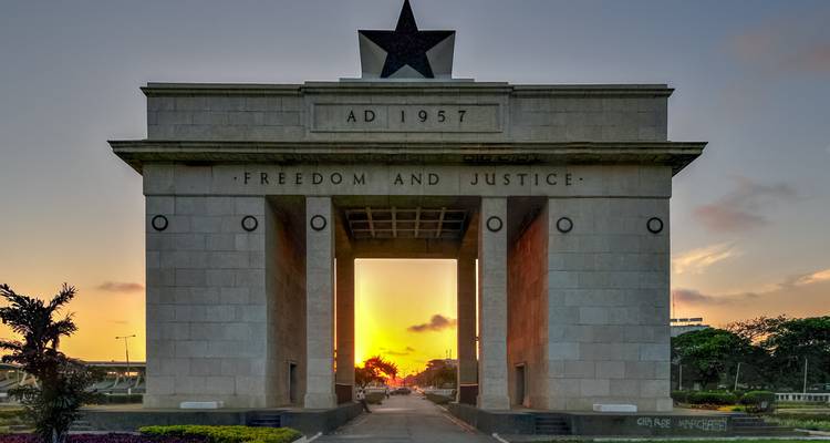 L'Arche de l'Indépendance du Ghana avec son étoile noire encadre un coucher de soleil vibrant à travers le portail central.
