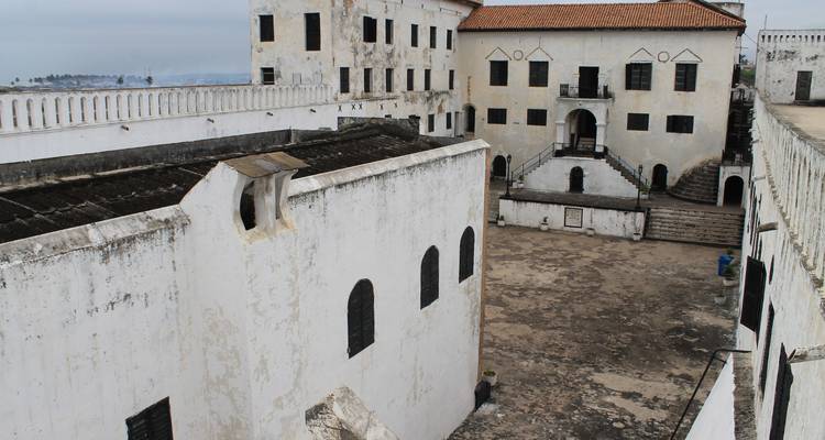 Murs blancs patinés par les intempéries et cour du château historique d'Elmina surplombant la côte.
