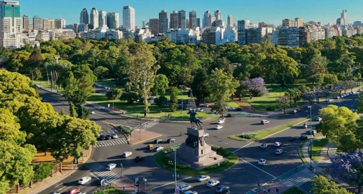 Aerial view of a leafy urban roundabout and skyline of modern high-rise buildings.