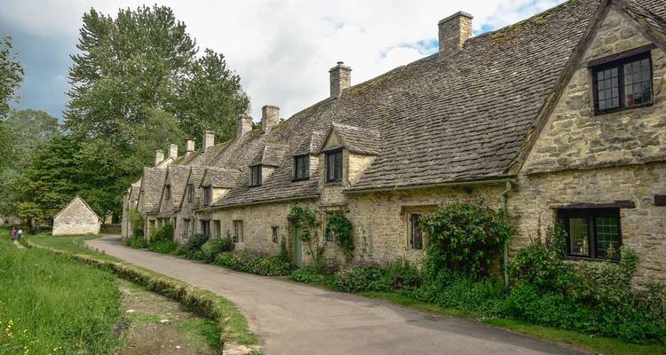 Historische Arlington Row aus honigfarbenen Häuschen mit Steinbedachung neben einer schmalen Gasse und grünem Randstreifen