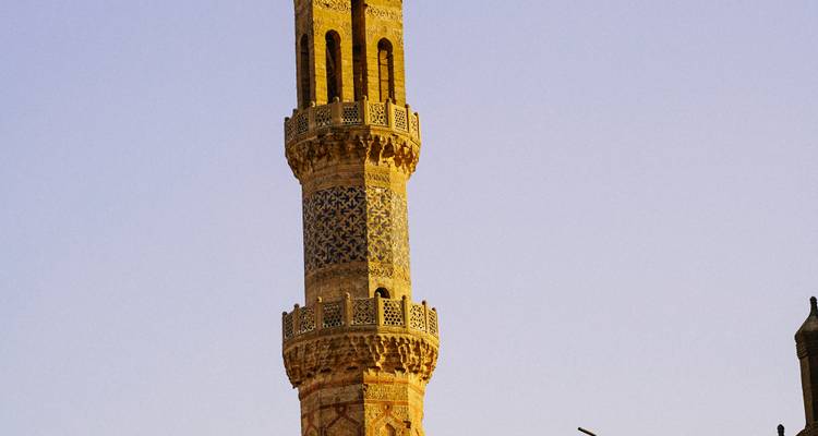 Grand minaret orné décoré de motifs de carreaux bleus se détachant sur un ciel de soirée dégagé