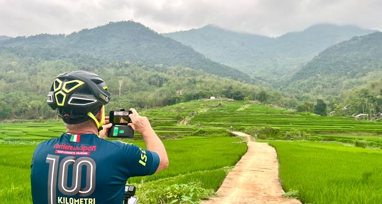 Un cycliste s'arrête pour photographier des rizières en terrasses sur fond de montagnes.