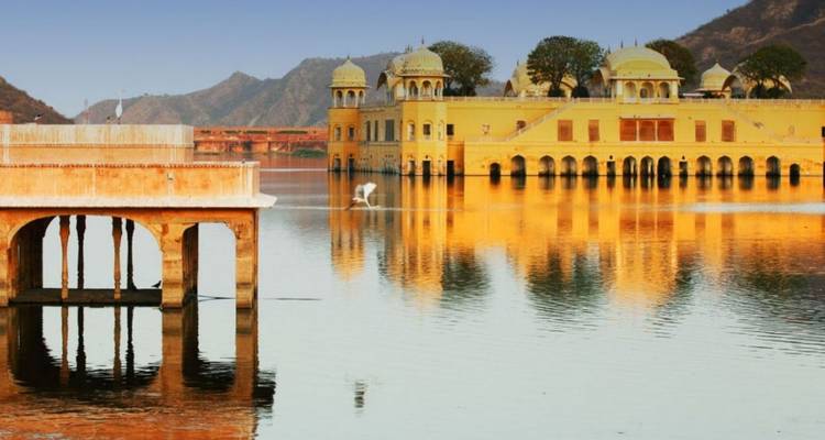 El palacio amarillo Jal Mahal reflejado en las aguas tranquilas del lago Man Sagar al amanecer.