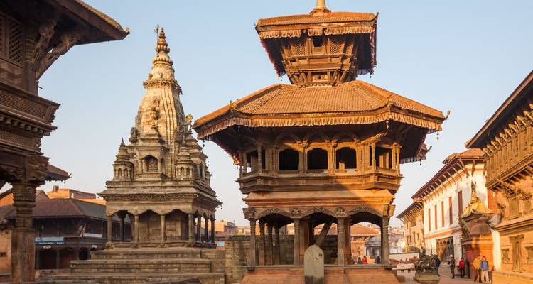 Templos pagoda históricos de la Plaza Durbar de Bhaktapur bañados en la cálida luz del atardecer con visitantes caminando alrededor.