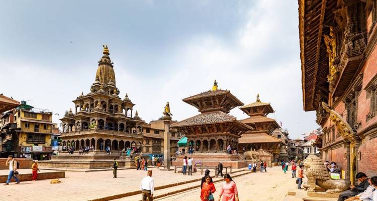 Vista amplia de la Plaza Durbar de Patan con templos, leones de piedra y lugareños paseando por la plaza.