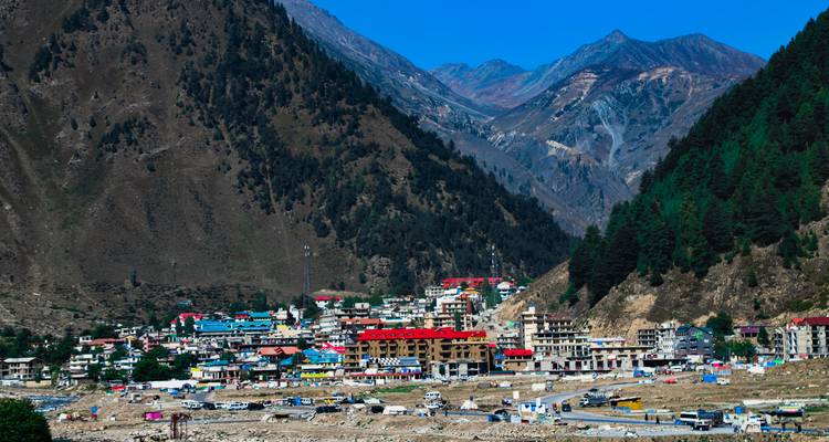 Mountain town of Naran nestled in a steep valley with colourful rooftops and towering peaks.
