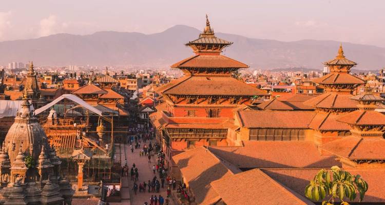 Abendlicht über dem Kathmandu Durbar Square mit mehrstöckigen Pagodentempeln and fernen Bergen.