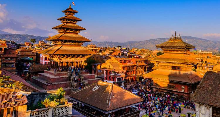 Sonnenbeschienene Tempel im Pagodenstil ragen über die belebten Dächer des Kathmandu-Tals und die geschäftigen Menschenmengen darunter empor.