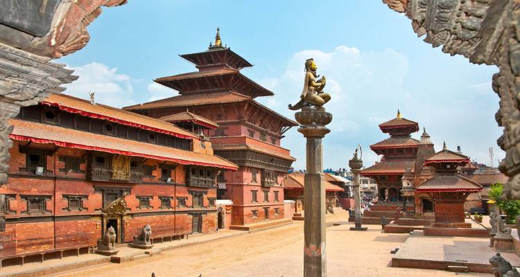 Historische Backsteintempel und skulptierte Säulen säumen einen ruhigen Platz unter einem strahlend blauen Himmel.
