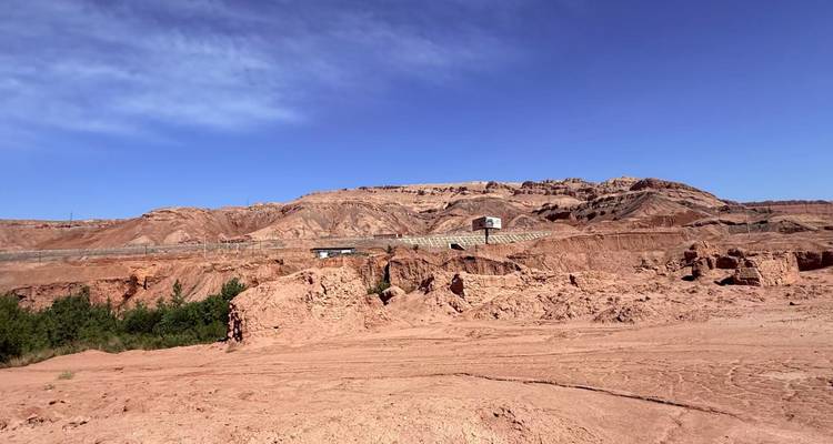 Erodierte rote Sandsteinhügel und verfallene Mauern erstrecken sich unter einem tiefblauen Wüstenhimmel.