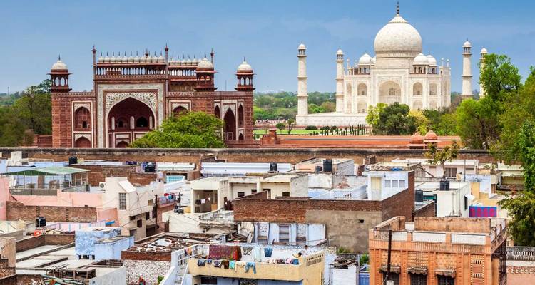 Stadtbild von Agra mit Taj Mahal und Eingangstor, die über den Dächern unter klarem blauem Himmel emporragen