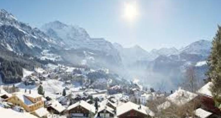Panoramische Winterlandschaft eines schneebedeckten Alpentals unter strahlender Sonne.
