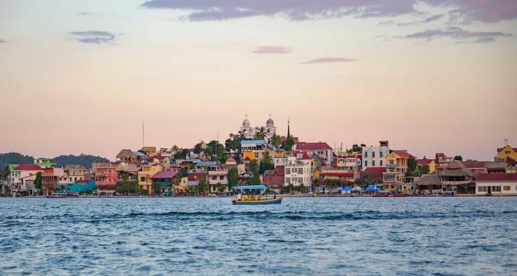 Los coloridos edificios costeros de la isla de Flores brillan bajo los cielos pastel del atardecer mientras un pequeño bote cruza el lago.