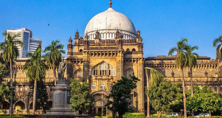 Vorderansicht des kuppelförmigen Prince of Wales Museums, umgeben von Palmen und blauem Himmel in Mumbai.