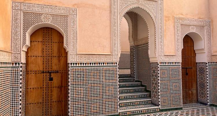 Eleganter marokkanischer Innenhof mit gefliesten Wänden, gewölbten Türöffnungen und mosaikverzierten Treppen.