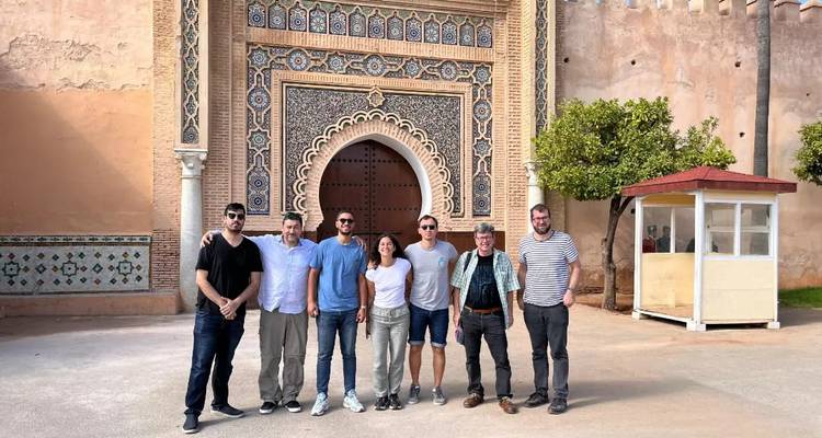 Gruppe von Reisenden posiert vor dem kunstvollen Bogentor Bab Mansour in Meknes.