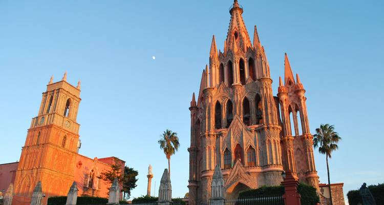 Le grès rose de la Parroquia de San Miguel Arcángel brille dans la chaude lumière du coucher de soleil sur un ciel dégagé.
