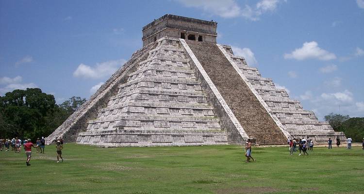La pyramide emblématique d'El Castillo s'élevant au-dessus de la place herbeuse à Chichen Itza sous un ciel bleu.