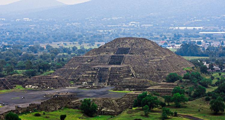 La massive Pyramide du Soleil domine l'ancienne cité de Teotihuacan avec des plaines vertes au-delà.