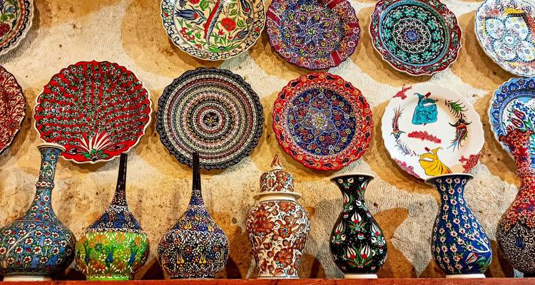Exposition murale d'assiettes et vases en céramique turque peints à la main aux couleurs vives dans une boutique traditionnelle.