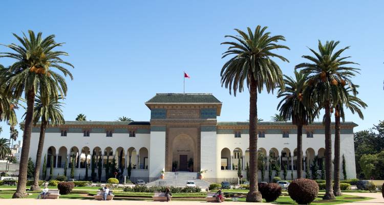 Place bordée de palmiers devant le bâtiment administratif historique de Casablanca sous un ciel bleu dégagé.