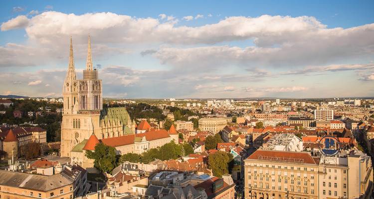 Luchtfoto van Zagreb met de twee torens van de kathedraal en rode daken badend in warm middaglicht.