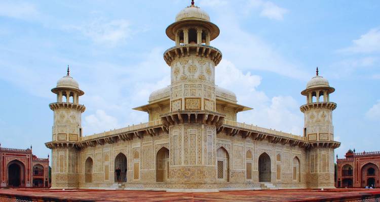 Elfenbeinfarbenes Itimad-ud-Daula-Mausoleum mit filigranen Pietra-dura-Arbeiten vor hellem Himmel.
