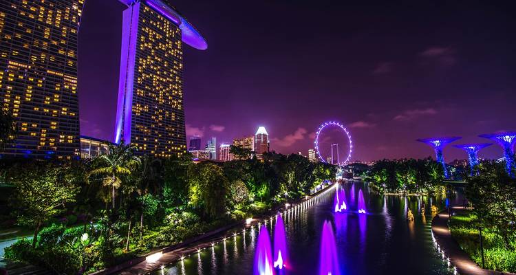Horizonte nocturno de Singapur con Marina Bay Sands, jardines iluminados y la noria de Singapur.