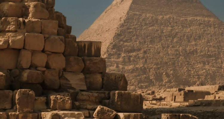 Nahaufnahme von Steinblöcken einer kleinen Pyramide mit der Großen Pyramide, die dahinter aufragt