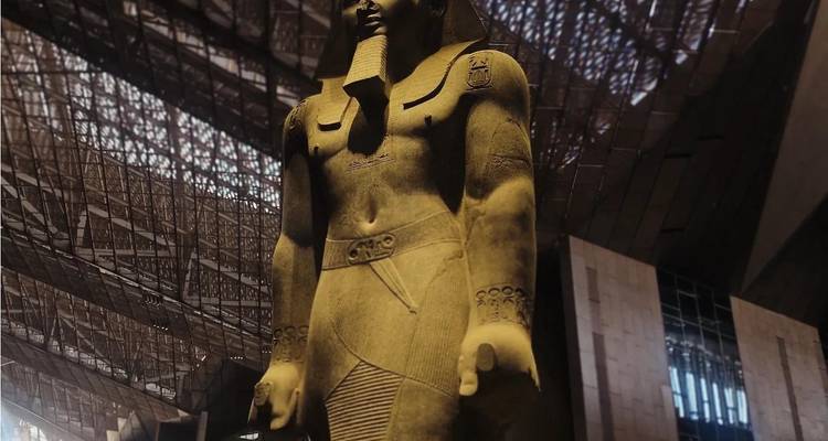 Kolossale Pharaonenstatue steht in modernem Museumsatrium mit gemusterter Decke