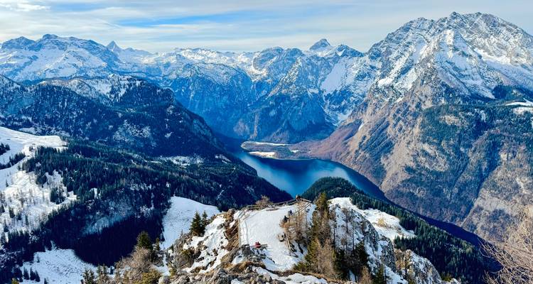 Crête montagneuse enneigée panoramique surplombant un lac bleu profond niché dans des vallées alpines spectaculaires