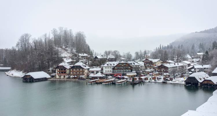 Village au bord du lac avec des hangars à bateaux en bois et des toits couverts de neige par une journée d'hiver grise